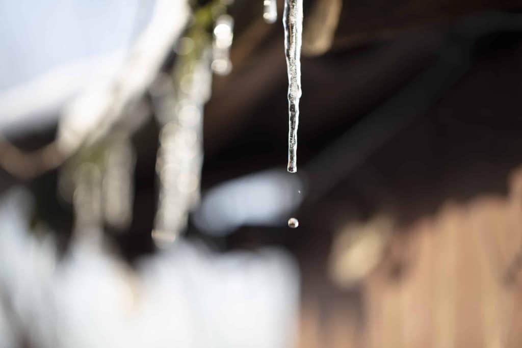 A water droplet coming from an icicle on a home's roof in spring Calgary