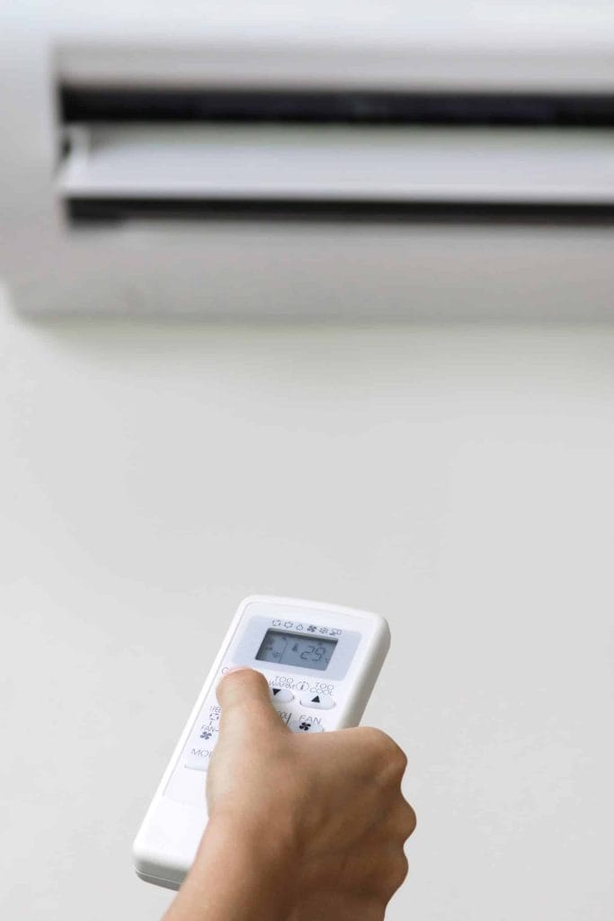 An individual operating an air conditioner in their home, demonstrating the significance of energy efficiency.