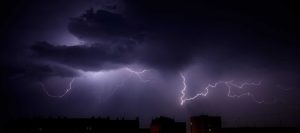 Bright branched lightning over the rooftops of urban buildings