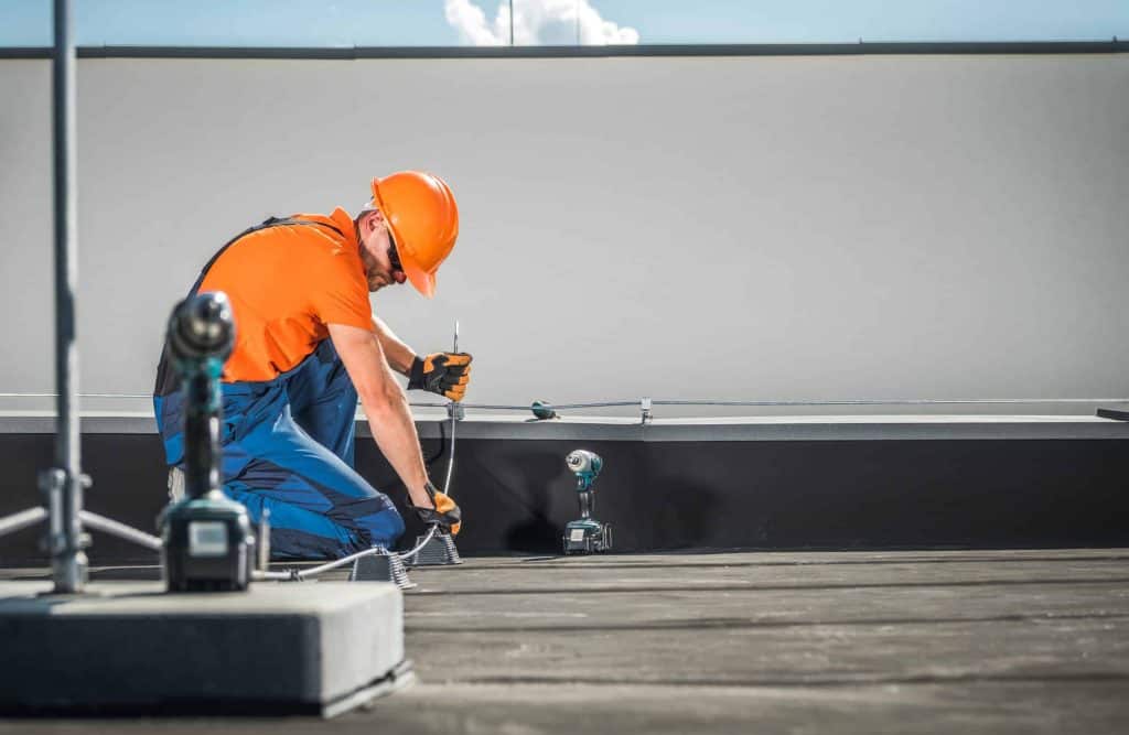 Caucasian Residential Building Lightning Protection System Installer in His 40s Finishing His Work on the Building Roof.
