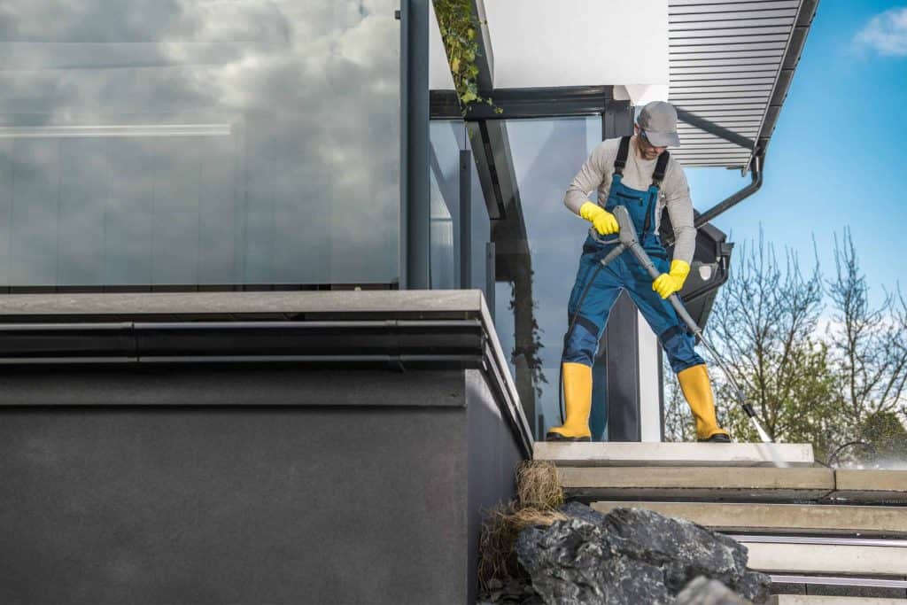A man using a pressure washer on a roof