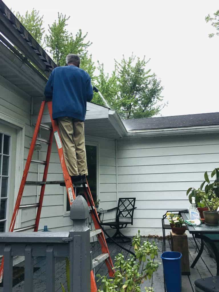 Man cleaning his gutters in the fall on his residential property