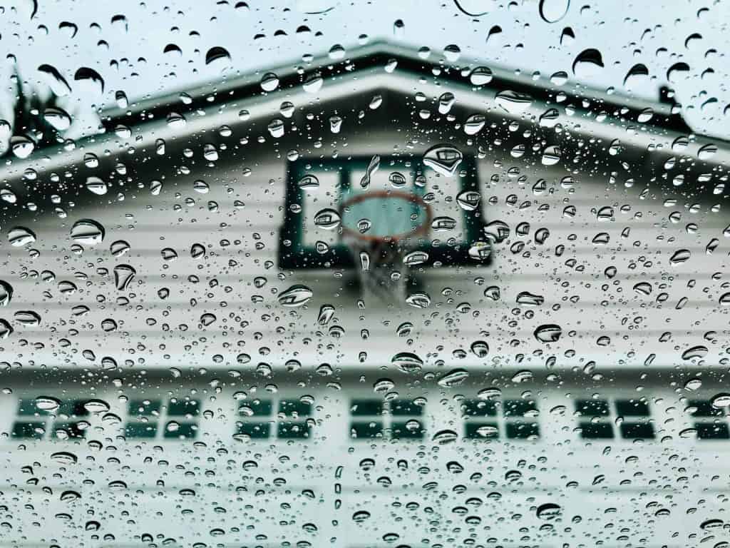 A photo of the front of a residential propriety with a basketball hoop above the garage with droplets on the lens.