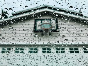 A photo of the front of a residential propriety with a basketball hoop above the garage with droplets on the lens.