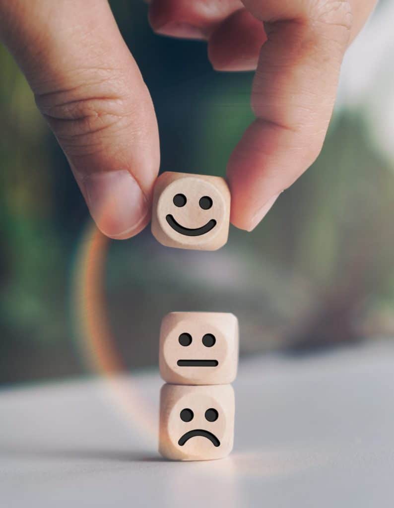 Smiling face and cart icon on a wooden cube, representing customer satisfaction and positive service ratings for Whalley’s Four Seasons Roofing in Calgary.