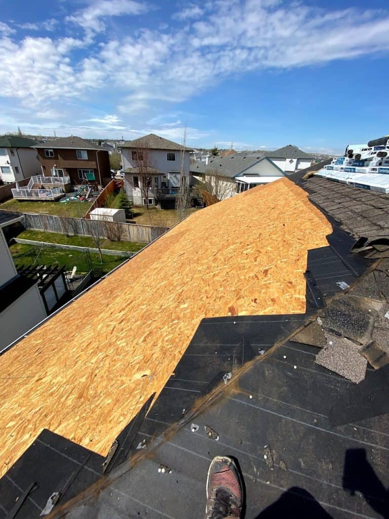 A Calgary roof being torn off and replaced, currently with the wood deck exposed.