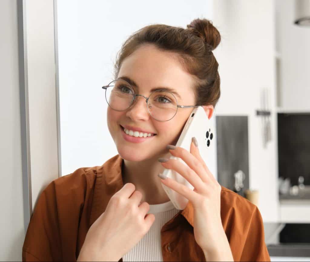 Portrait of happy smiling young woman at home, talking on mobile phone, calling whalley's and having nice conversation, about her new roof.