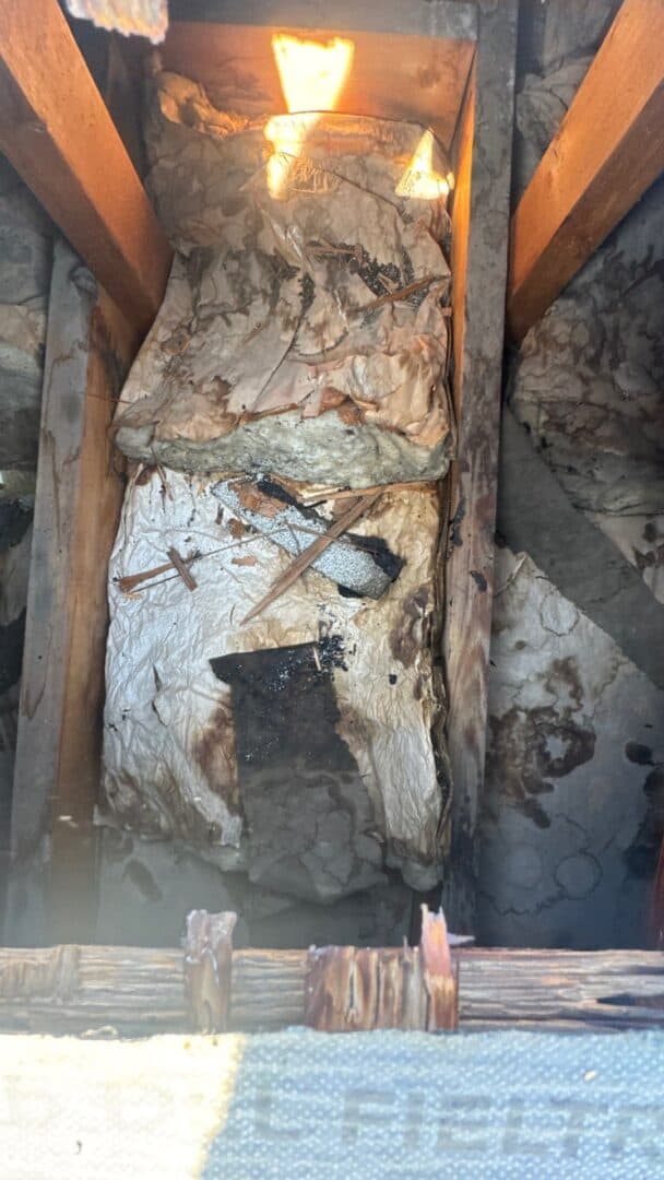 Water stains and damaged insulation in an attic caused by roof leaks, showing moisture intrusion and deterioration of building materials.