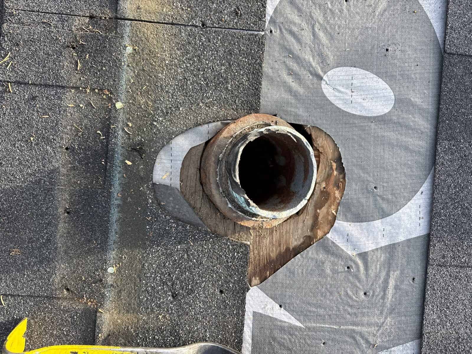 Rotted wood around a plumbing vent opening in an asphalt shingle roof