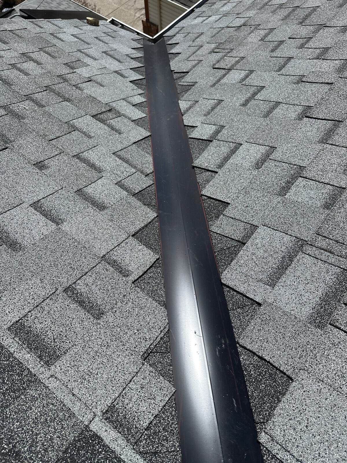 Completed metal roof valley tied into fresh asphalt shingles on a Calgary home